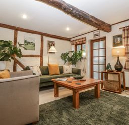 A living room with a sofa, coffee table, and plants at Magpie Cottage in Worcester