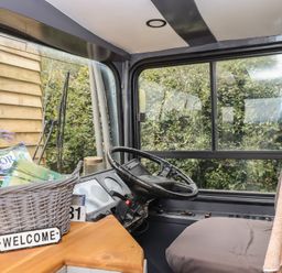 A vehicle cabin with a steering wheel and basket at The Bus on the Hill 