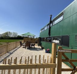 An outdoor area with a green bus, table and chairs at The Bus on the Hill in Huntsham near Bampton, Devon