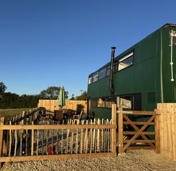 An outdoor seating area with a green bus at The Bus on the Hill, Huntsham near Bampton, Devon