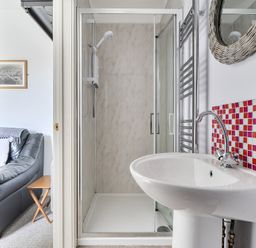 A bathroom featuring a shower, sink, and towel radiator at The Nook in Praa Sands