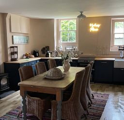 A kitchen featuring a dining table with chairs and a stove at High Dyke Cottage