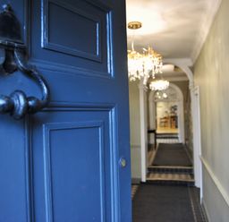A view of a hallway with chandelier and door at ASH HOUSE in Wincanton