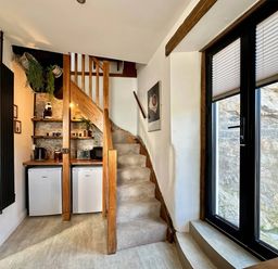 A staircase leading to a kitchen area with a refrigerator and coffee maker at 