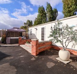 An outdoor area with a hot tub and seating at Lodge in Talacre