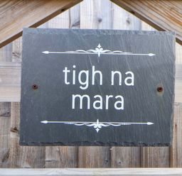 A slate sign reading tigh na mara on a wooden fence at Lodge Talacre