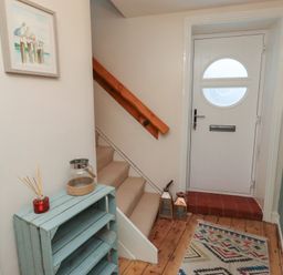 A hallway with a staircase and door at Corner Cottage in Seahouses