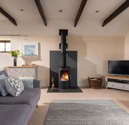 A living room with a fireplace and a television at The Granary near St Merryn