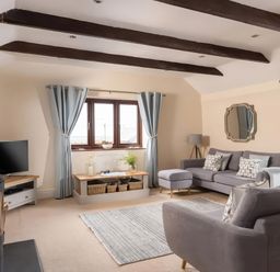 A living room with a tv, sofa, and curtains at The Granary near St Merryn