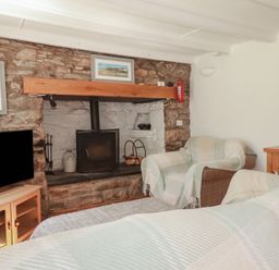 A living room with a fireplace and television at Blowing House Cottage near Perranporth