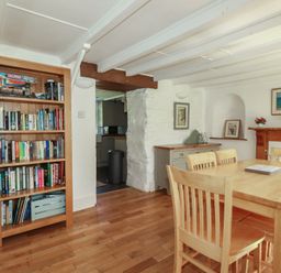 A dining room with a bookshelf and a dining table at Blowing House Cottage near Perranporth