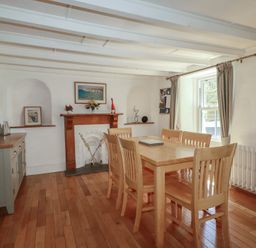 A dining room with a wooden table and chairs at Blowing House Cottage near Perranporth