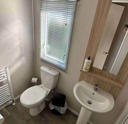 A bathroom with a toilet, sink, and window