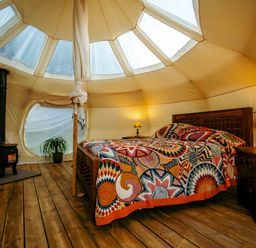 A bedroom with a bed and wood stove in a glamping tent