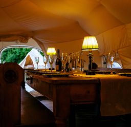 A dining room with a table set at a glamping site in a tent