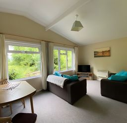 A living room with a sofa, television and dining table at Baillie Chalet