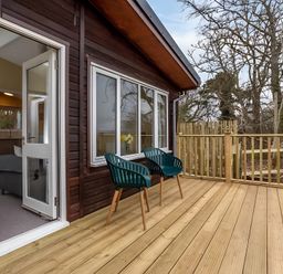 A deck with green chairs and wooden railing at Kilninver Chalet