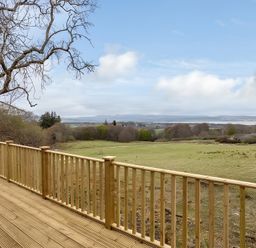 A view from a deck overlooking a grassy landscape at Kilninver Chalet
