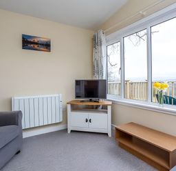 A living room with a TV and armchair at Kilninver Chalet