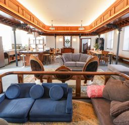 A living room with various seating and a kitchen area at Capel Llani in Llanidloes