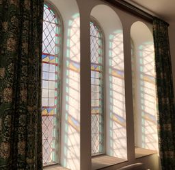 Stained glass windows with curtains in a room at Capel Llani Llanidloes