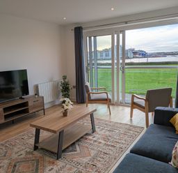 A living room with a television and furniture at Sea Fern House - 36, Poole