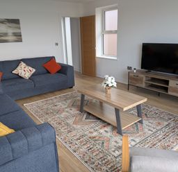 A living room with a coffee table, sofas, and a television at Sea Fern House - 36 in Poole