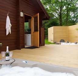 An outdoor area with a hot tub and champagne at Gisburn Forest Lodge
