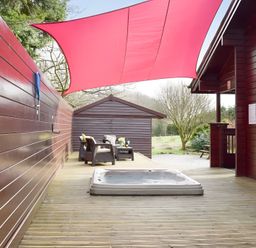 An outdoor space with a hot tub and chairs at Gisburn Forest Lodge