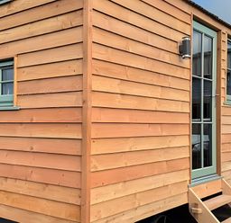 A wooden cabin exterior with windows and door at Y Nyth