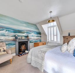 A bedroom with a bed and armchair at Lil Nauti in Fowey
