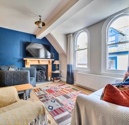 A living room with a television and sofa at Lil Nauti in Fowey