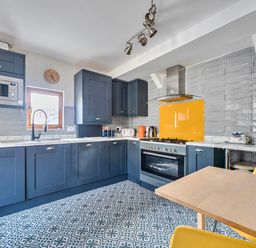A kitchen with appliances and a dining table at Lil Nauti Fowey