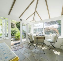A conservatory with a table and chairs at Bwthyn Nain in Harlech