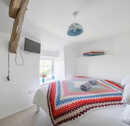 A bedroom with a bed and television at Bwthyn Nain in Harlech