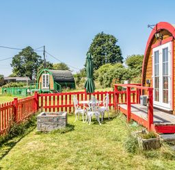 A garden with glamping pods and outdoor seating at St Austell Glamping St Austell