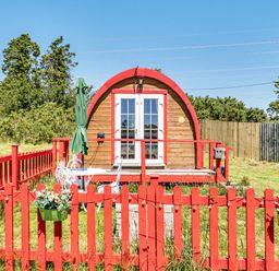 A cabin with a red fence and patio at St Austell Glamping in St Austell