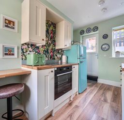 A kitchen with a fridge, oven, and bar stool at 20 Main Street in Heysham