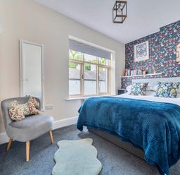A bedroom with a bed, chair, and window at 20 Main Street in Heysham