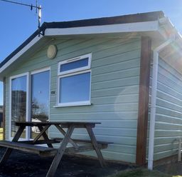 A cabin with a table and bench outside at Embury