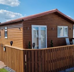 A wooden cabin with a fence and door at 50 Bridlington