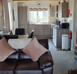 A living room with a sofa and kitchen area at 50 Bridlington