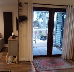A living room with a sofa and door leading to a deck at Gowrie Lodge in Blairgowrie
