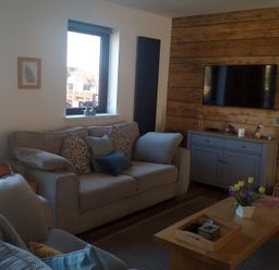 A living room with a couch, television, and coffee table at Gowrie Lodge in Blairgowrie