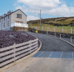 A house with a driveway and fence at Groeslon Uchaf in Caernarfon