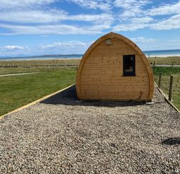 An outdoor view of a wooden pod with a window at Kirkapol Beach Pod - Flow Isle of Tiree