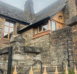An outdoor view of a house with stone walls and windows at 4 Bickington Road Barnstaple