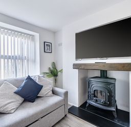 A living room with a sofa, television, and fireplace at Blue Haven in Penmaenmawr