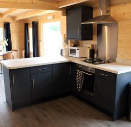 A kitchen with black cabinets and a dining table at Cotswold Nights Away 1 Evesham