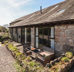 An outdoor seating area with a table and chairs at Tullythwaite Barn in Kendal
